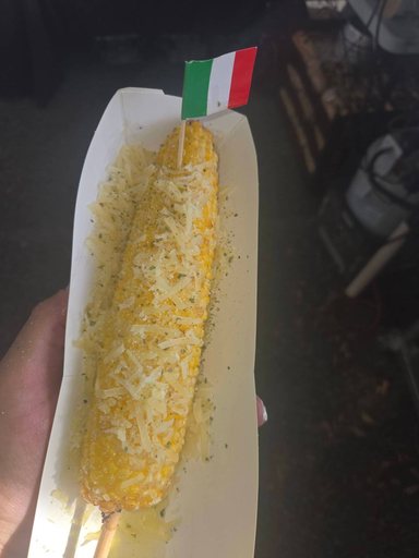 Parmesan street corn on a stick, topped with shredded parmesan and herbs